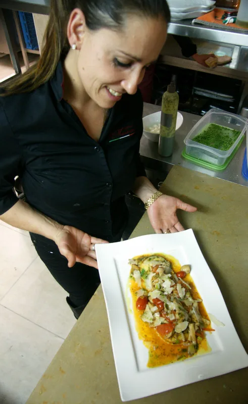 Medewerkster van Da Marianna presenteert een bord ravioli met champignons en parmezaan